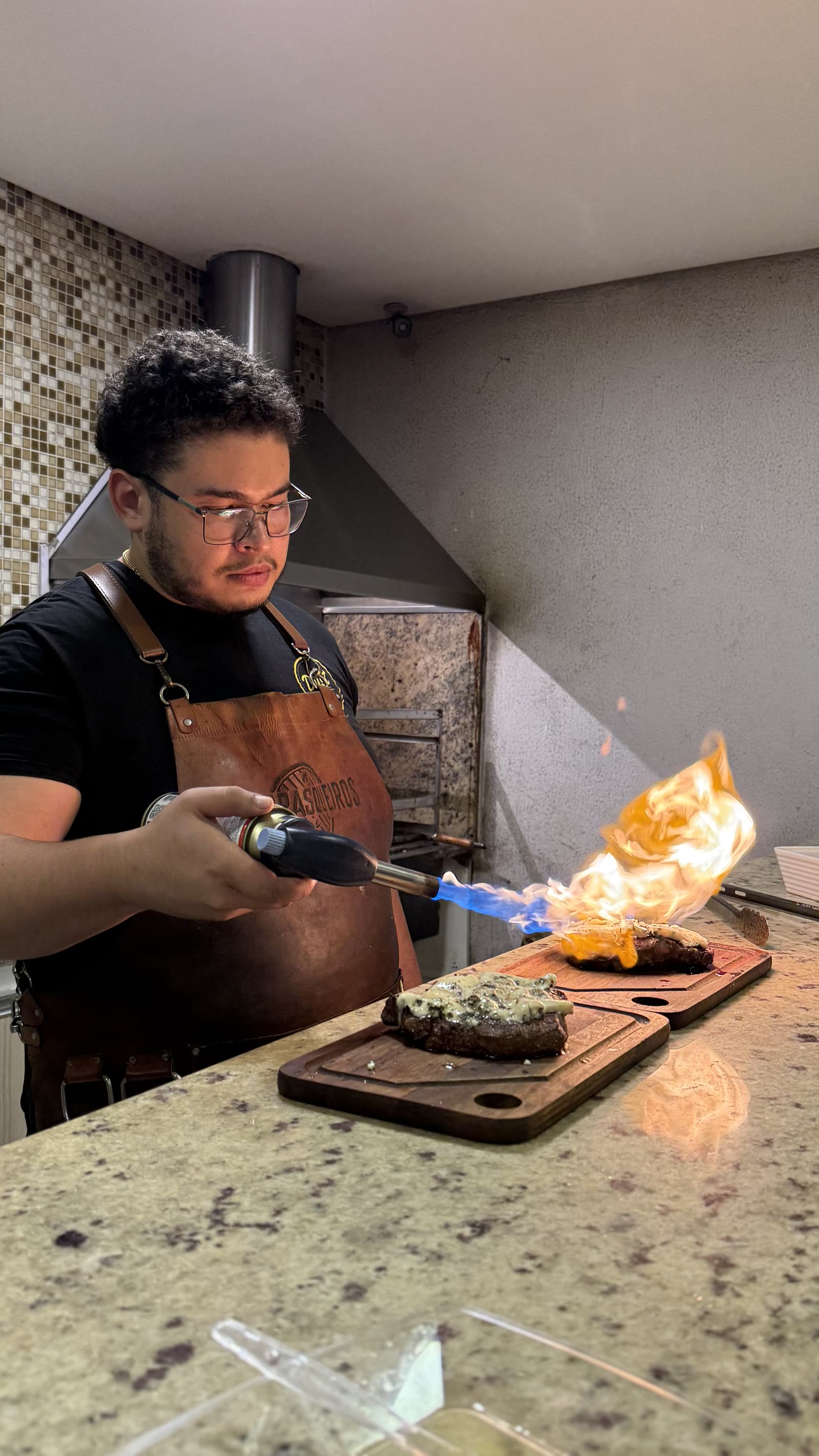 Assador finalizando corte com gorgonzola no maçarico durante evento