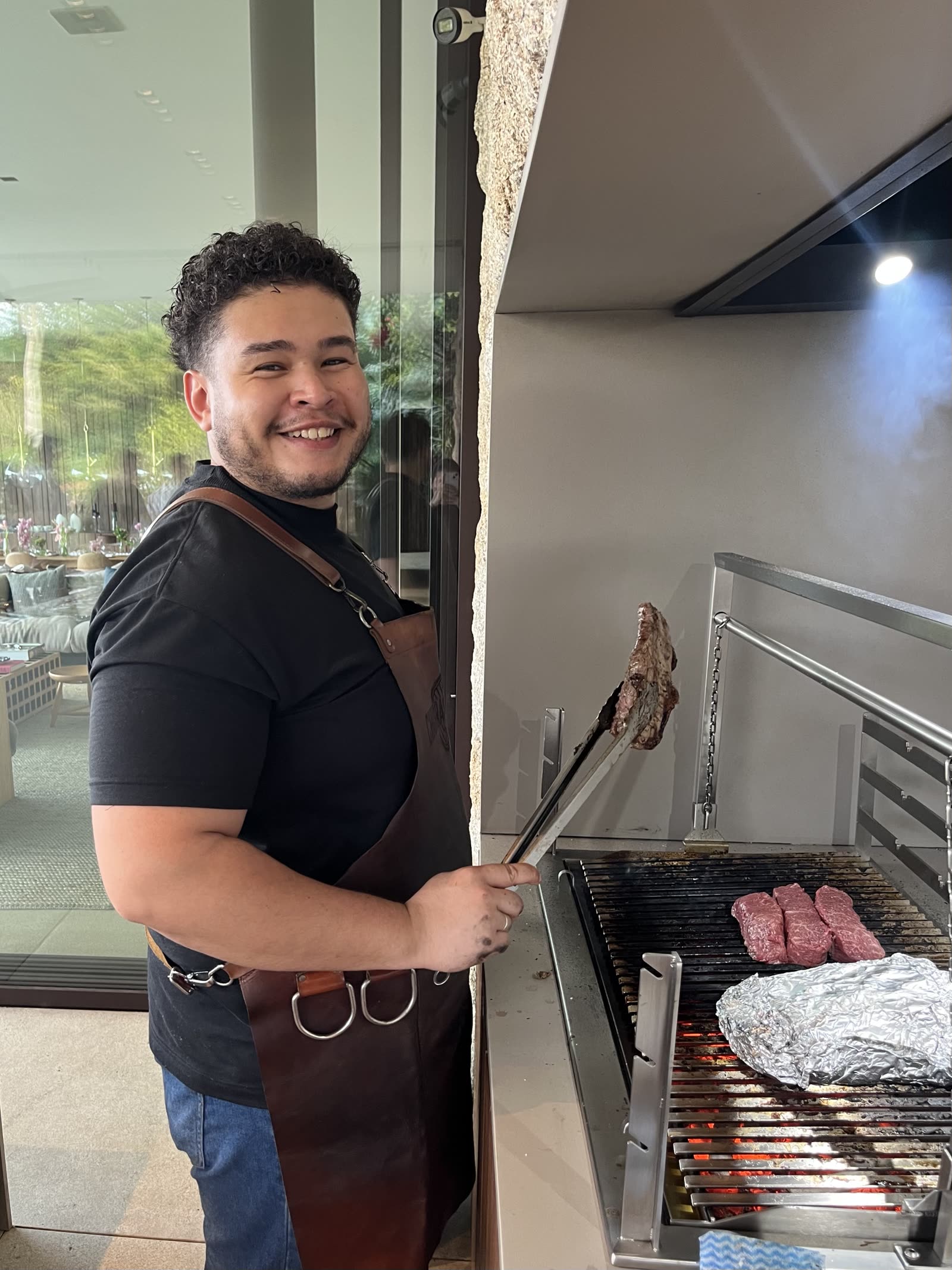 Assador da Dust sorrindo enquanto vira os cortes na parrilla